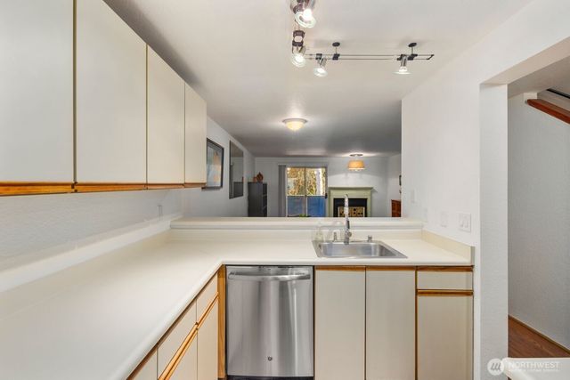 a view of a kitchen with granite countertop a sink and dishwasher with wooden floor