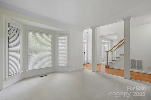a view of an empty room with window and wooden floor