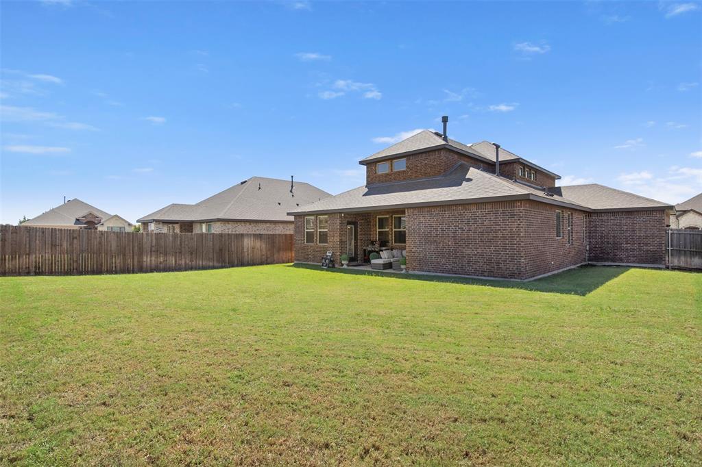 4125 Fern Loop Forney, TX 75126 - Photo 29 of 40 Expansive grassy yard with a wooden privacy fence, a brick exterior, a covered patio, and multiple windows