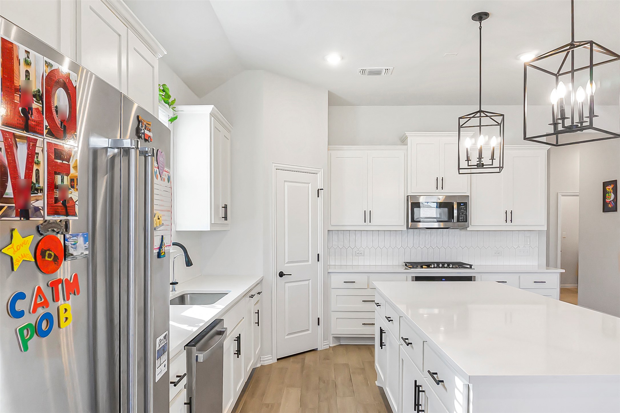 1016 Calendula Trail Georgetown, TX 78628 - Photo 10 of 40 Kitchen with stainless steel appliances, white cabinets, a kitchen island, and light wood-style floors
