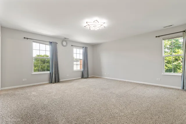 a view of a big room with windows and chandelier fan