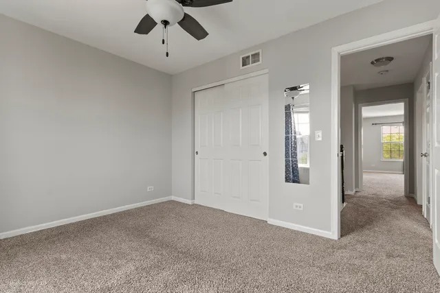 an empty room with closet and a chandelier fan