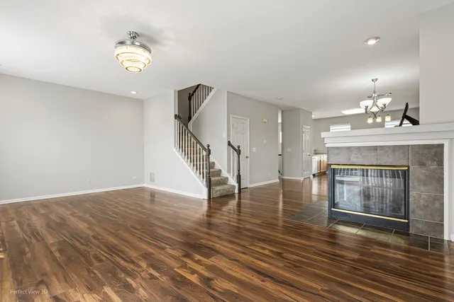 a view of an empty room with wooden floor fireplace and a window