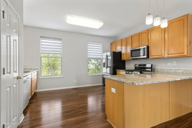 a kitchen with stainless steel appliances granite countertop a sink a stove a refrigerator cabinets and wooden floor