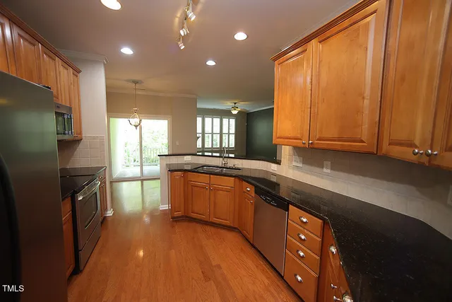 a large kitchen with stainless steel appliances granite countertop a refrigerator a sink dishwasher a stove and white countertops with wooden floor