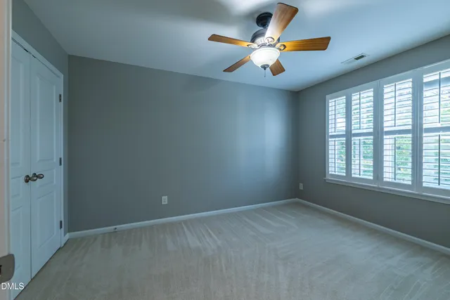 an empty room with windows and a ceiling fan