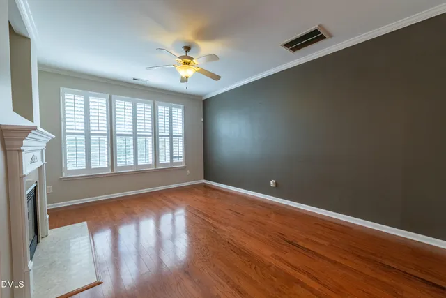 a view of an empty room with wooden floor and window