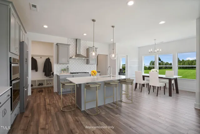 a kitchen with stainless steel appliances a dining table chairs stove and white cabinets