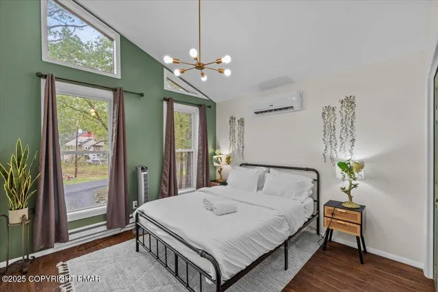 a living room with furniture floor to ceiling window hardwood floor and a flat screen tv