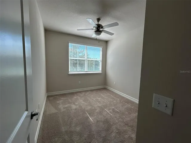 an empty room with a ceiling fan and a window