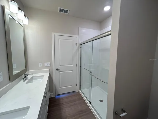 a bathroom with a double vanity sink mirror and shower