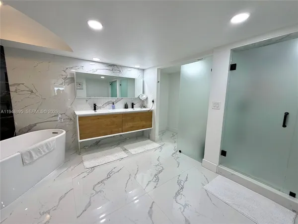 a bathroom with a tub sink shower and mirror