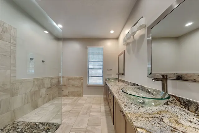 a bathroom with a granite countertop sink a mirror and shower