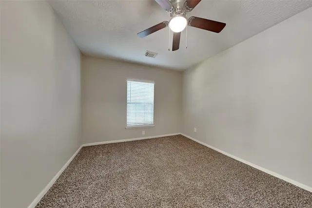 an empty room with a chandelier fan and windows