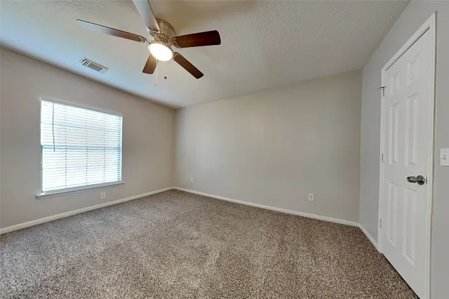 an empty room with ceiling fan and windows