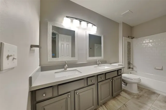 a bathroom with a double vanity sink toilet mirror and bathtub