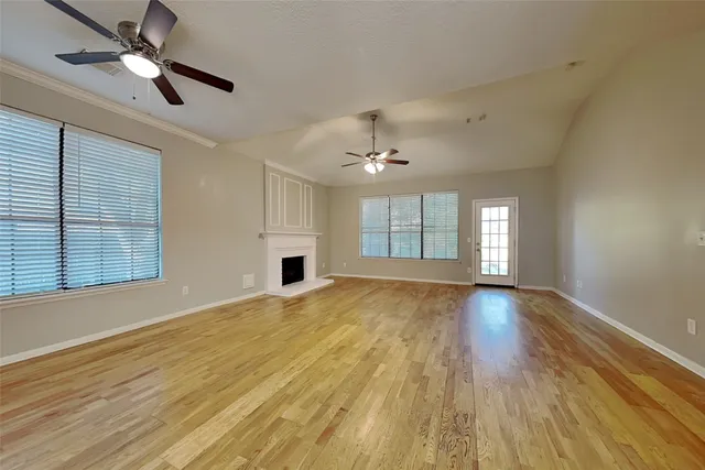 a view of an empty room with a window and wooden floor