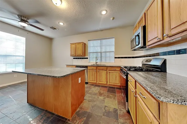 a kitchen with stainless steel appliances granite countertop a sink stove and microwave