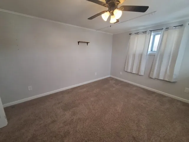 an empty room with a chandelier fan and windows