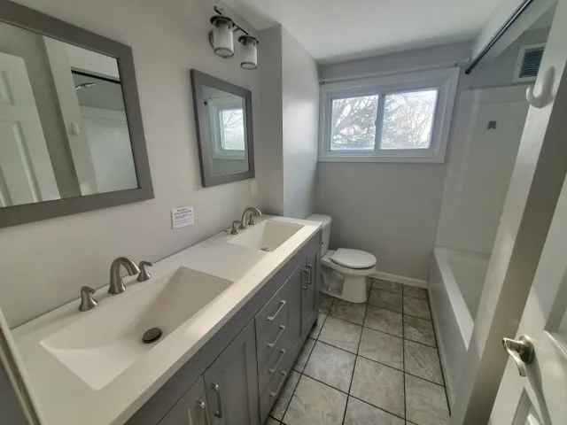 a bathroom with a double vanity sink toilet and a mirror