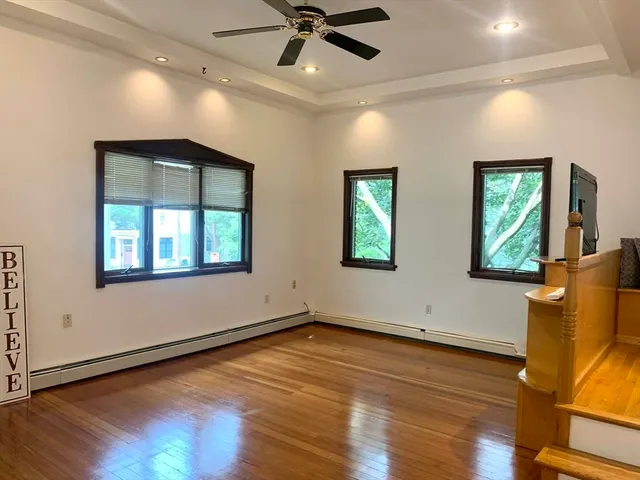 a view of an empty room with window and wooden floor
