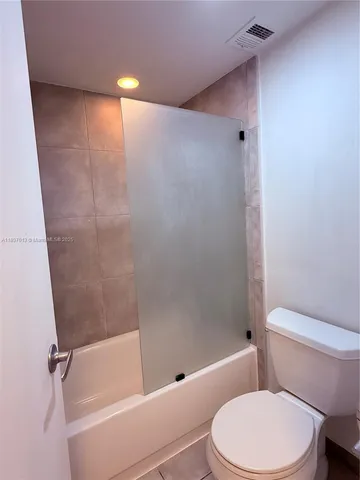 a white toilet sitting next to a bath tub and a shower
