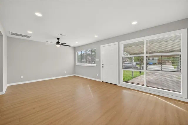 a view of an empty room with a window and wooden floor