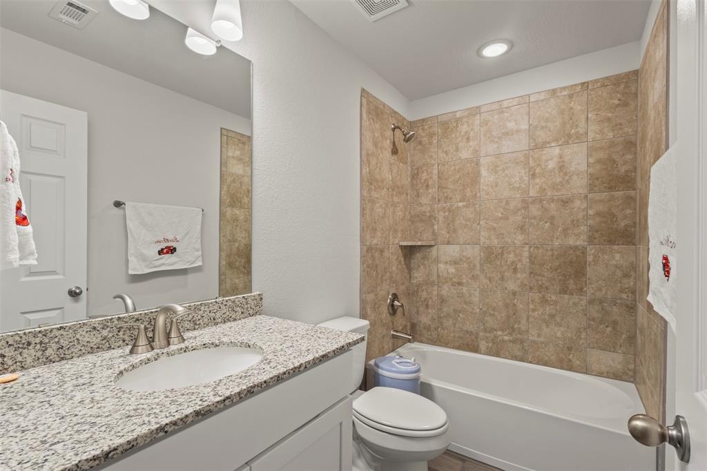551 Ruthye Lane Pilot Point, TX 76258 - Photo 25 of 40 a bathroom with a granite countertop toilet a sink and a bathtub
