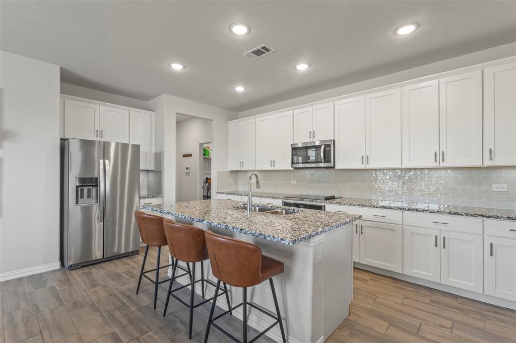 551 Ruthye Lane Pilot Point, TX 76258 - Photo 8 of 40 a kitchen with stainless steel appliances granite countertop a stove top oven a refrigerator a sink and white cabinets