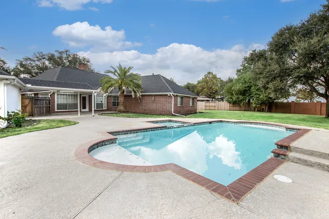 a view of swimming pool with outdoor seating and house in the background