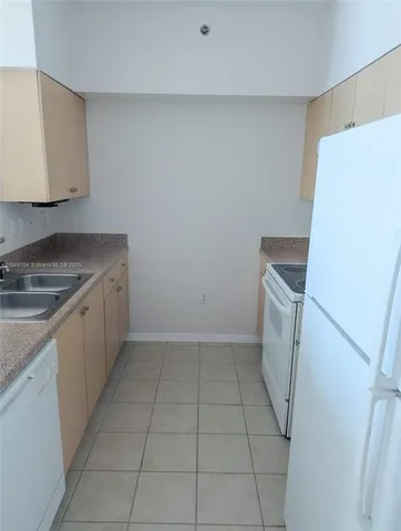a kitchen with a sink a refrigerator and a stove top oven