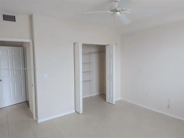 an empty room with a ceiling fan and entryway
