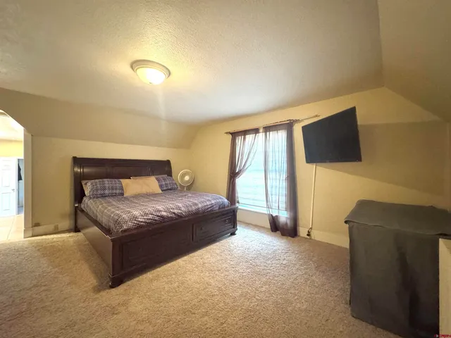 a spacious bedroom with a bed and a flat screen television