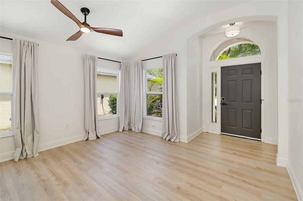6226 Blueflower Court Lakewood Ranch, FL 34202 - Photo 9 of 81 an empty room with wooden floor mirror and windows