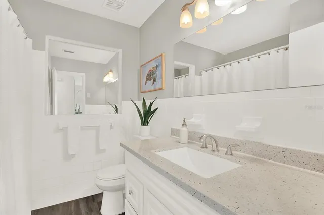 a bathroom with a granite countertop sink mirror and a toilet