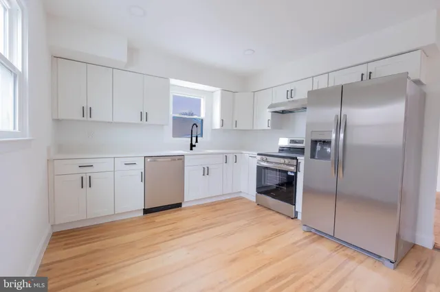 a kitchen with granite countertop a refrigerator oven a sink and cabinets