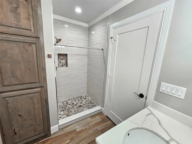 a view of an empty room with wooden floor and a ceiling fan
