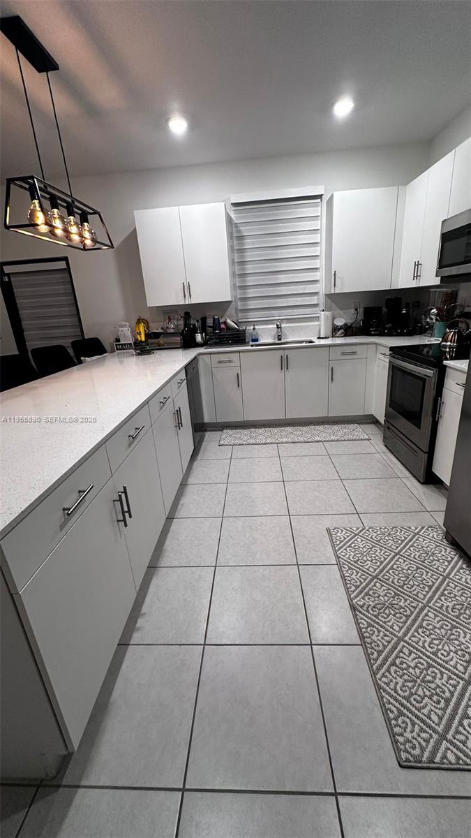 12961 Southwest 230th Street Miami, FL 33170 - Photo 27 of 39 a kitchen with stainless steel appliances kitchen island granite countertop a refrigerator a stove a sink and a microwave