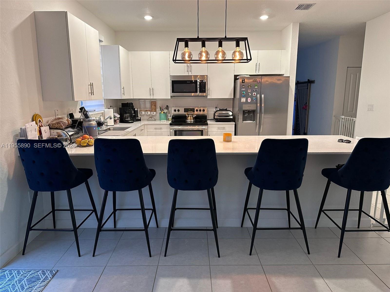 12961 Southwest 230th Street Miami, FL 33170 - Photo 9 of 39 a kitchen with stainless steel appliances kitchen island granite countertop a table and chairs in it