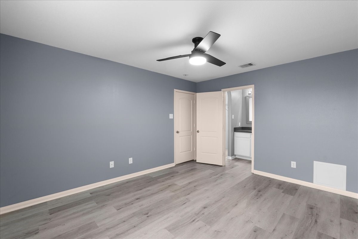 5727 Treasure Cove Road Cove, TX 77523 - Photo 10 of 20 a view of an empty room with wooden floor and a ceiling fan
