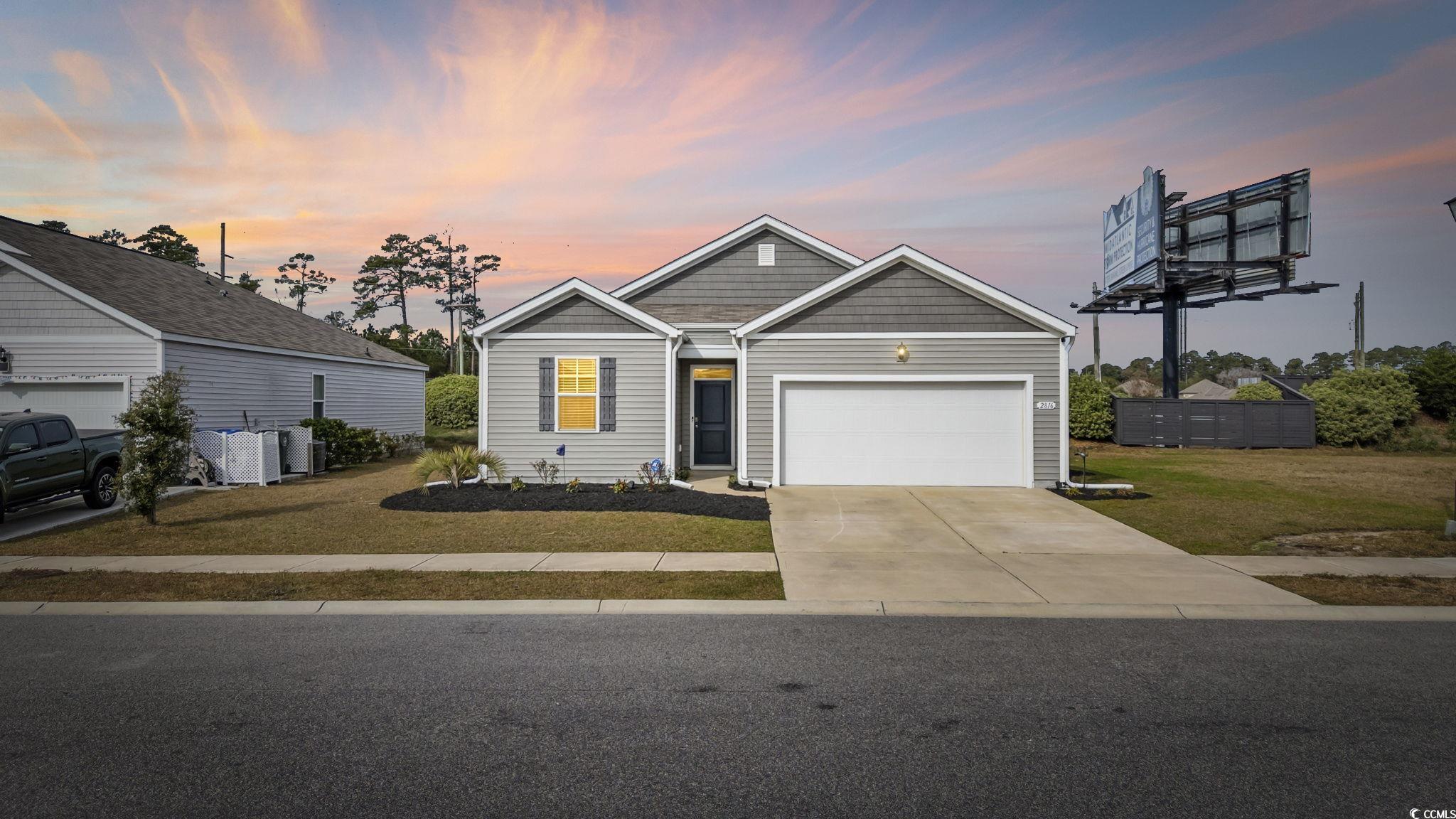 View of front of home with driveway, an attached garage, and a front lawn