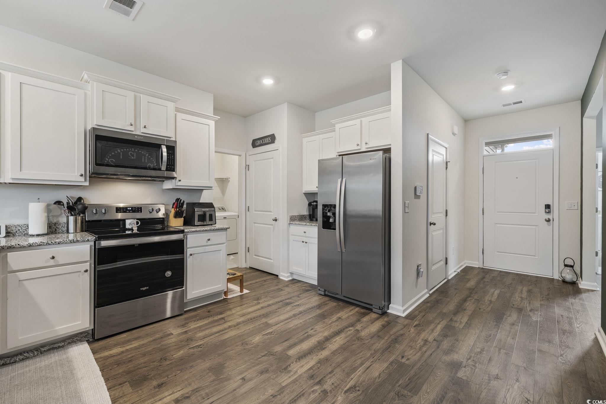 2816 Ophelia Way Myrtle Beach, SC 29577 - Photo 4 of 39 Kitchen with appliances with stainless steel finishes, white cabinetry, dark wood-style floors, light stone countertops, and washer / clothes dryer