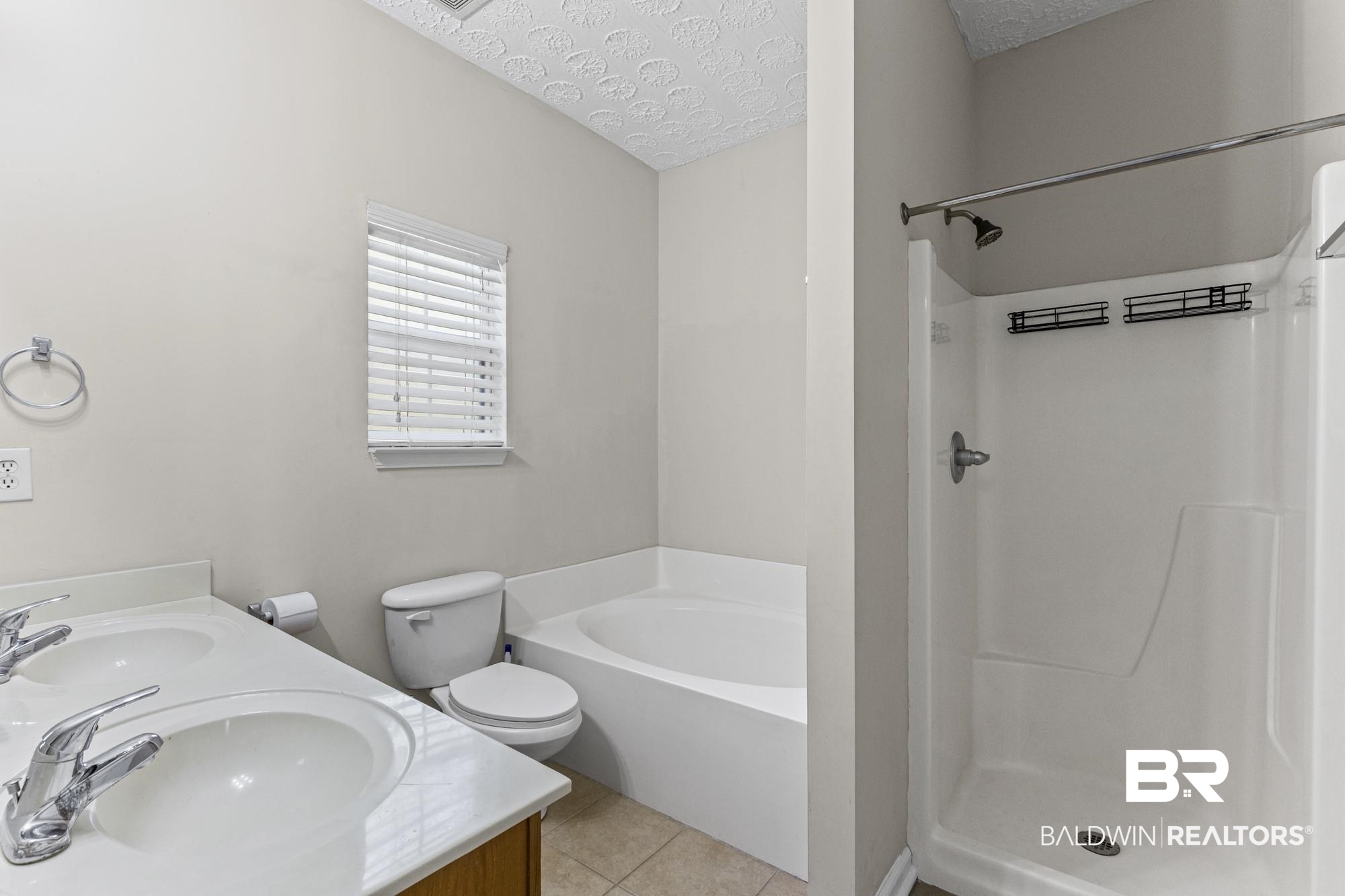 1153 Sloane Cove Foley, AL 36535 - Photo 18 of 25 Bathroom with double vanity, a textured ceiling, a stall shower, a bath, and light tile patterned floors