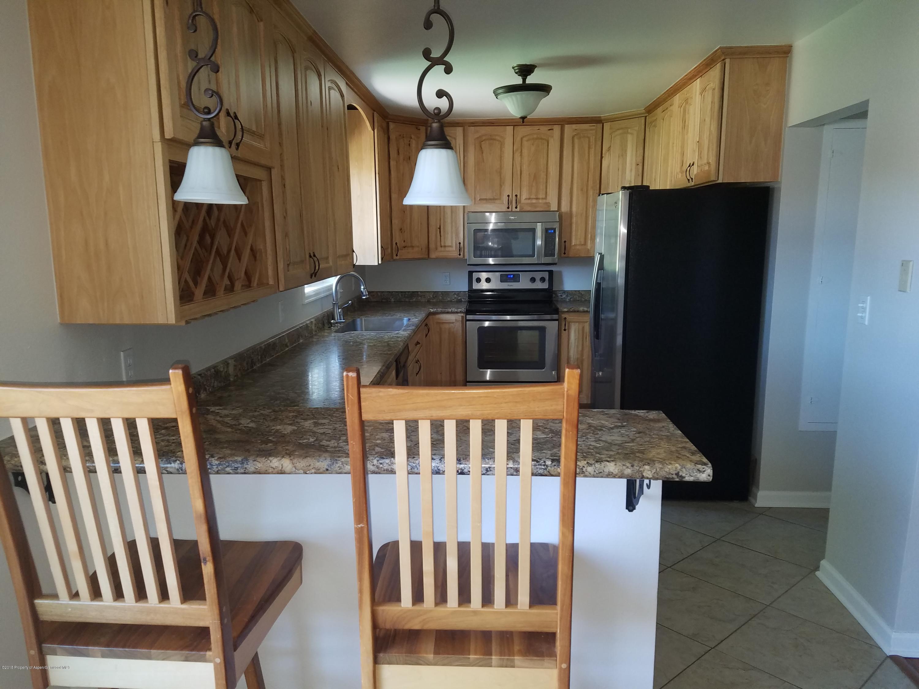730 Green Street Craig, CO 81625 - Photo 7 of 34 a kitchen with stainless steel appliances granite countertop a refrigerator a stove a sink and a dining table with wooden floor