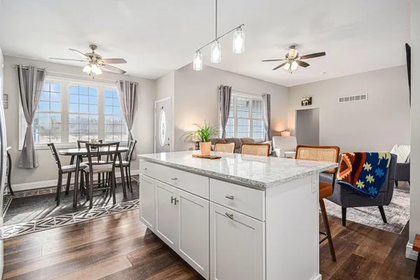 a open kitchen with stainless steel appliances granite countertop a stove dining table and chairs with wooden floor