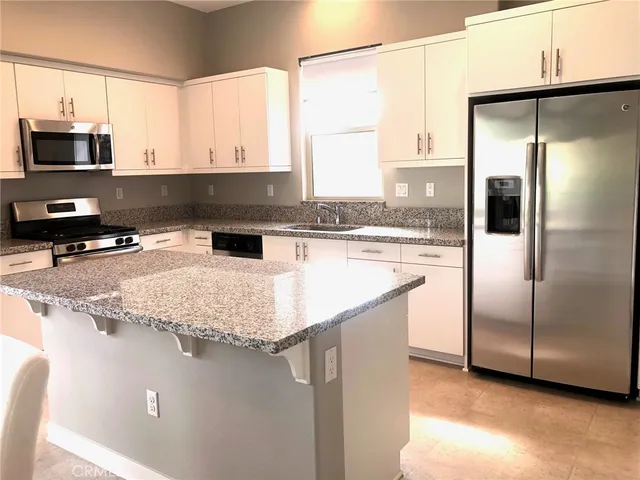 a kitchen with granite countertop white cabinets and white appliances