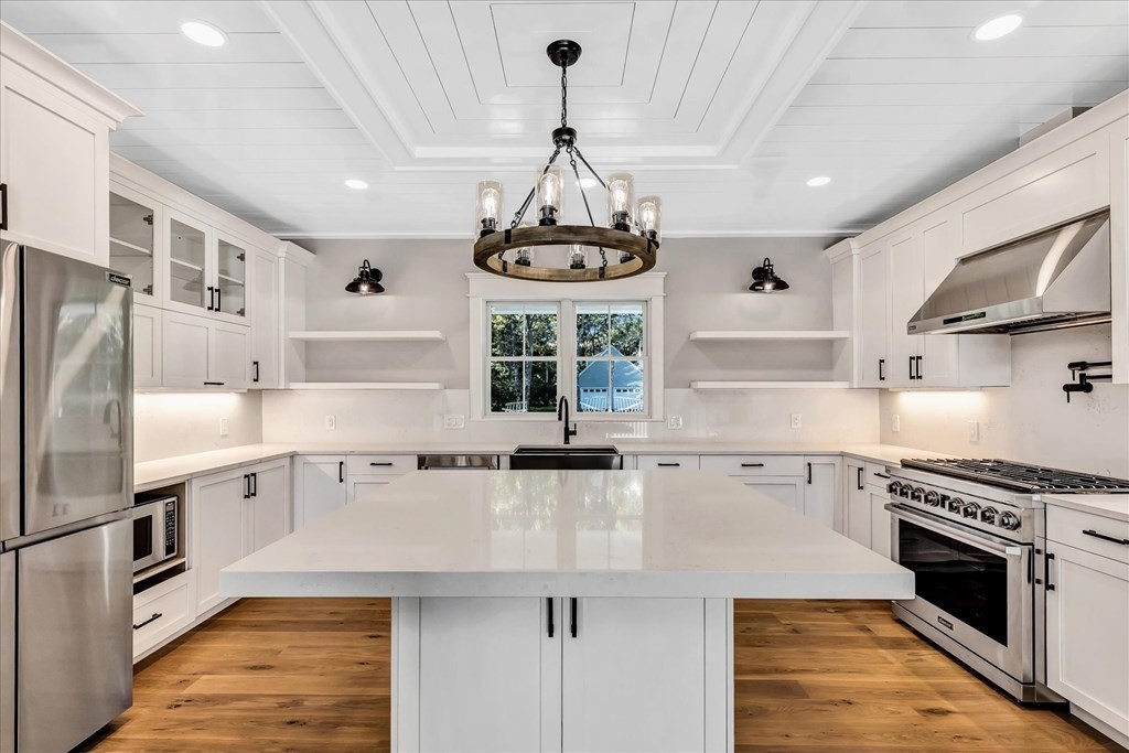 58 Amos Landing Road Mashpee, MA 02649 - Photo 22 of 42 a kitchen with stainless steel appliances a sink a stove a chimney a refrigerator and cabinets