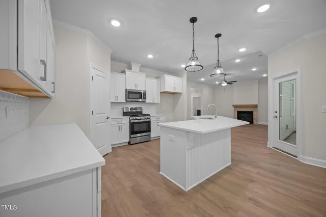a large kitchen with kitchen island a stove a sink a center island and a wooden floor