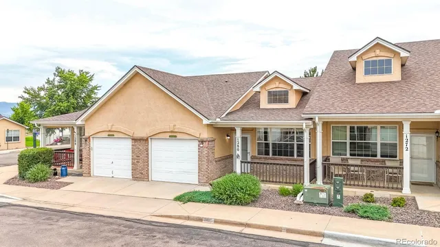 a view of a brick house with a yard plants and large tree