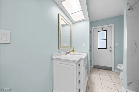 a bathroom with a granite countertop sink a toilet and mirror